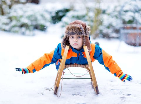 young boy on toboggan in snow istk