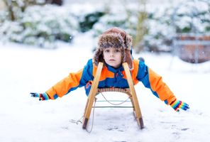 young boy on toboggan in snow istk