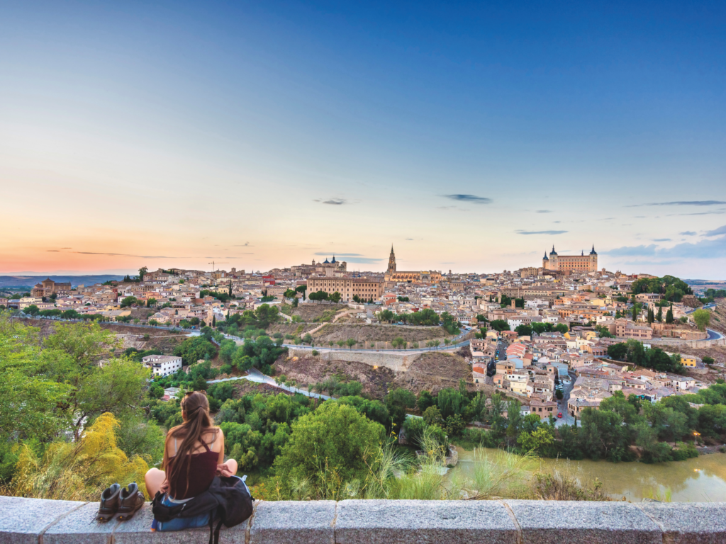 Picture of person sitting on a wall with a view of Toledo in the background